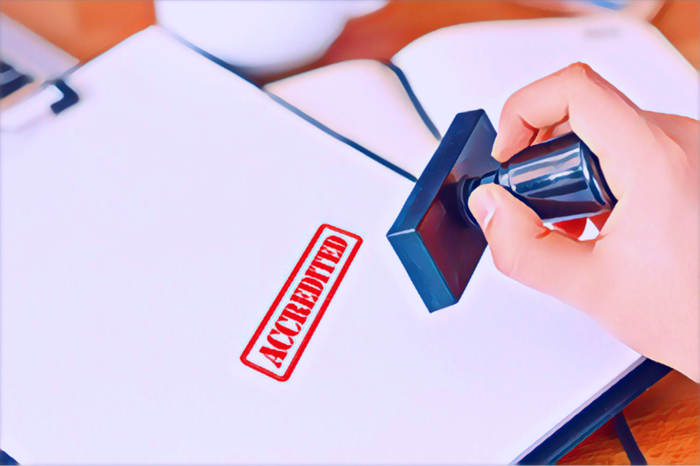 Close up of a hand holding a red stamp saying 'Accredited' which has just been stamped onto a report